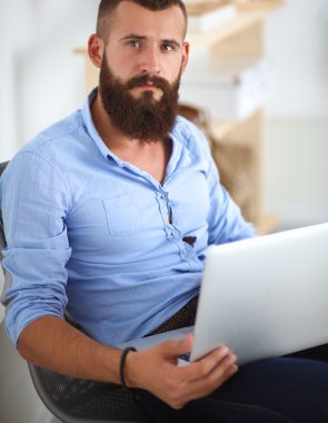 Yakışıklı genç adam dizüstü bilgisayarda oturuyor ve çalışıyor.