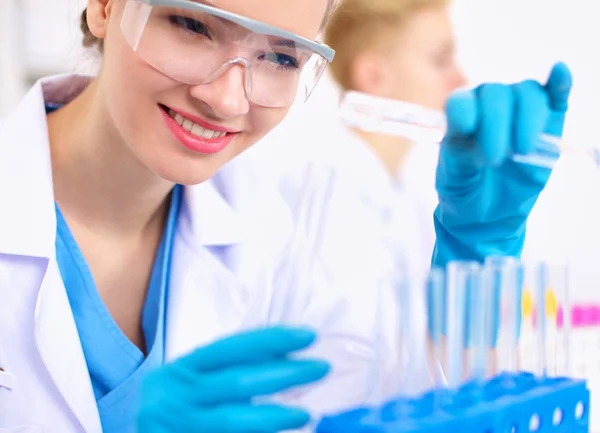 Woman researcher is surrounded by medical vials and flasks, isolated on white background — Stock Photo, Image