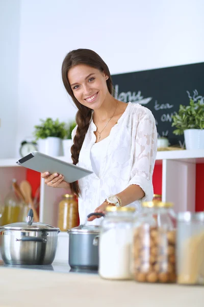 Mujer joven usando una tableta para cocinar en su cocina —  Fotos de Stock