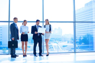 Toplantı sırasında dizüstü bilgisayarla sunum yapan bir grup iş adamı