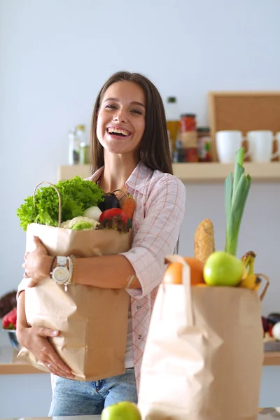 Young woman holding grocery shopping bag with vegetables