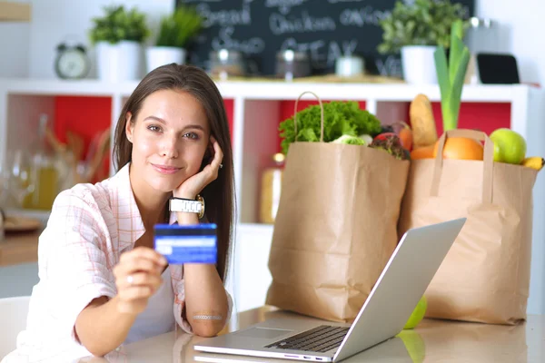 Lachende vrouw online winkelen met behulp van Tablet PC- en creditcard in keuken — Stockfoto