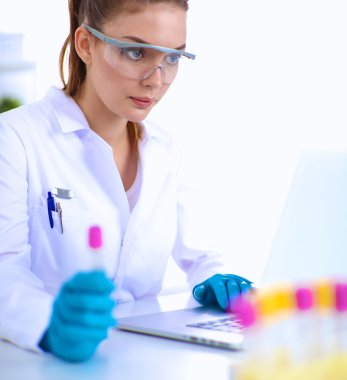 Kadın araştırmacı, beyaz şişeler ve şişelerle çevrili.