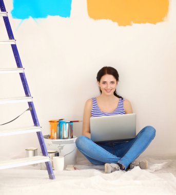 Yeni daire dizüstü bilgisayar ile oturup, boyama sırasında genç kadın portre