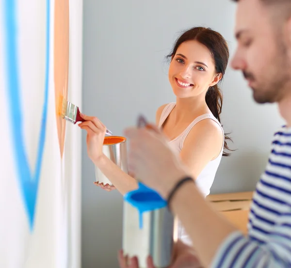 Portrait de heureux sourire jeune couple peinture mur intérieur de la maison neuve — Photo