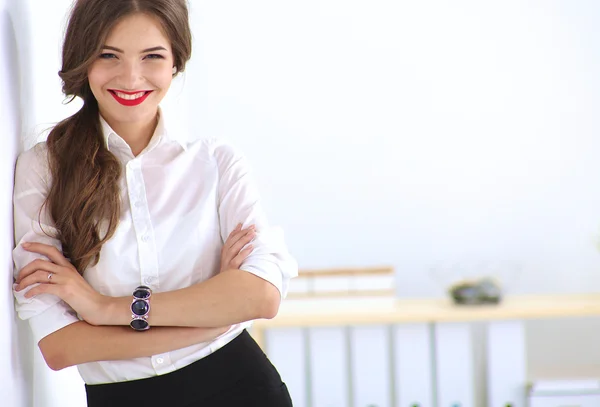 Attractive businesswoman standing near wall in office — Stock Photo, Image