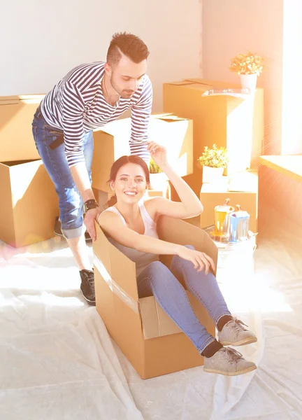 Casal feliz se divertindo e montando em caixas de papelão em nova casa — Fotografia de Stock