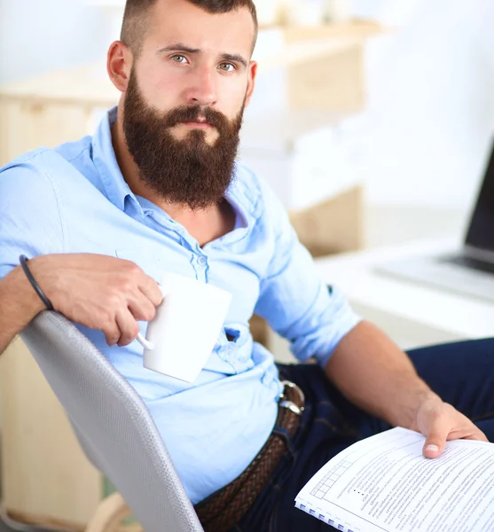 Молодой бизнесмен сидит на стуле в офисе — стоковое фото