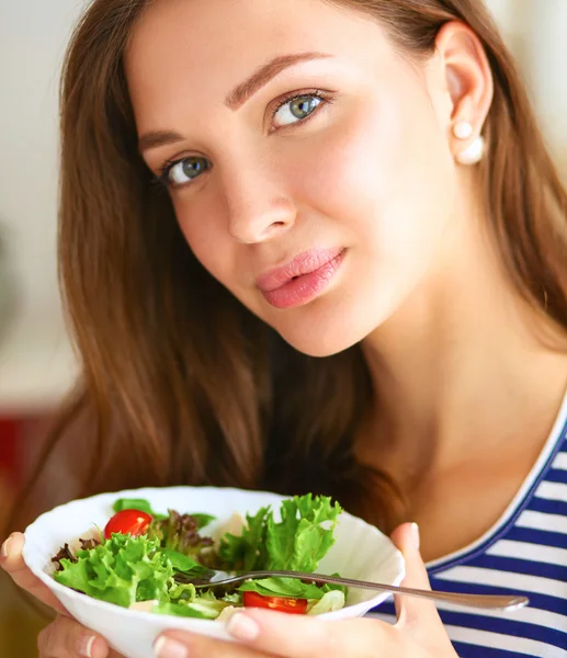 Giovane donna mangiare insalata e tenere un'insalata mista — Foto Stock