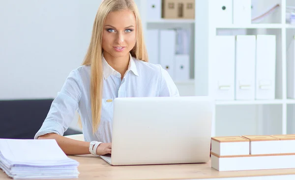 Attractive businesswoman sitting on a desk with laptop in the office — Stock Photo, Image