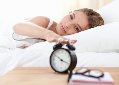 Evdeki yatak odasında uyuyan genç kadın ve çalar saat.