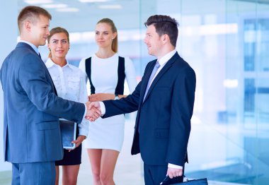 İki başarılı iş adamının el sıkışırken tam boy görüntüsü.