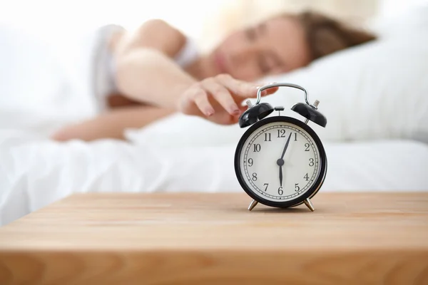 Young sleeping woman and alarm clock in bedroom at home Stock Photo