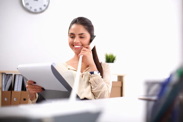 Jovem empresária sentada na mesa e conversando ao telefone — Fotografia de Stock