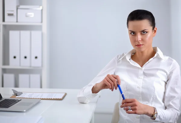 Aantrekkelijke zakenvrouw zit op een bureau met laptop in het kantoor — Stockfoto