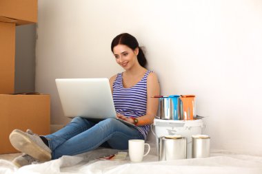 Yeni daire dizüstü bilgisayar ile oturup, boyama sırasında genç kadın portre