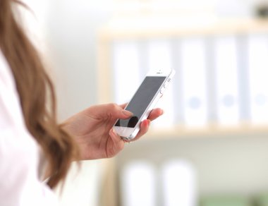 İş kadını ofiste oturan akıllı telefonuyla mesaj gönderiyor.