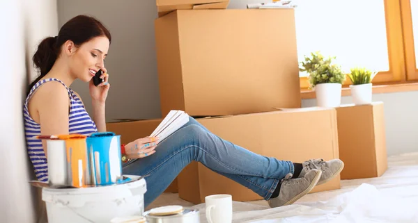 Vrouw verf kleur kiezen uit staal voor nieuwe huis zittend op houten vloer — Stockfoto