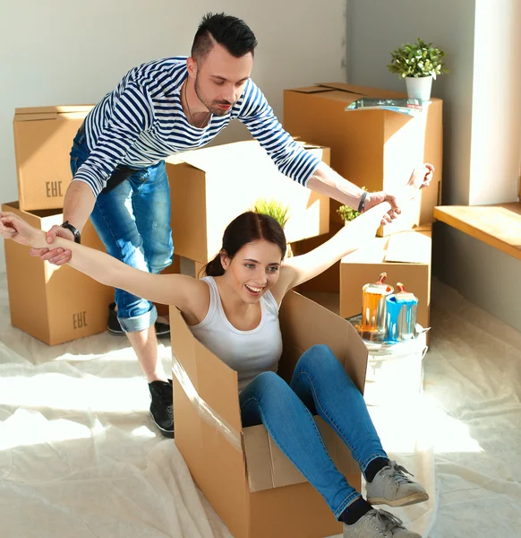 Casal feliz se divertindo e montando em caixas de papelão em nova casa — Fotografia de Stock