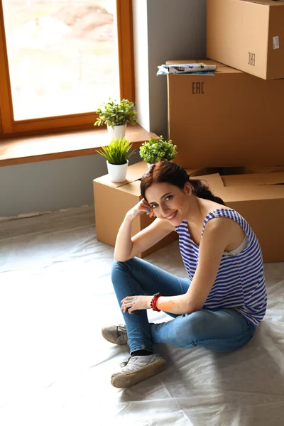 Mulher em uma nova casa com caixas de papelão — Fotografia de Stock