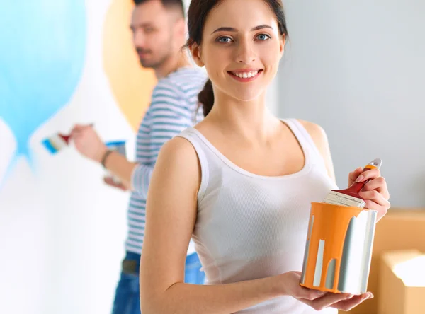 Retrato de feliz joven pareja sonriente pintando la pared interior de la nueva casa —  Fotos de Stock