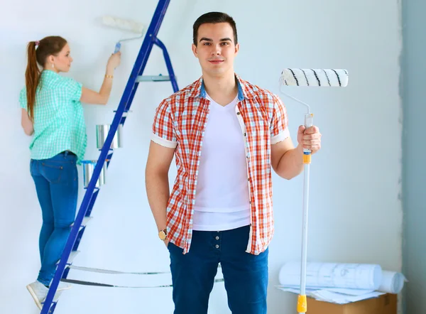 Portrait de heureux sourire jeune couple peinture mur intérieur de la maison neuve — Photo