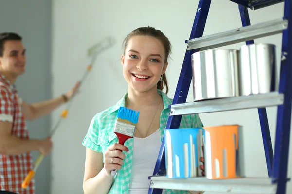 Retrato de feliz joven pareja sonriente pintando la pared interior de la nueva casa — Foto de Stock
