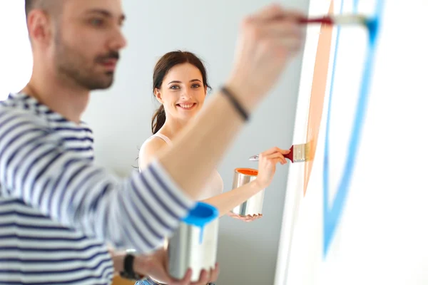 Retrato de feliz joven pareja sonriente pintando la pared interior de la nueva casa —  Fotos de Stock