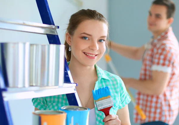 Porträt eines glücklich lächelnden jungen Paares beim Bemalen der Innenwand des neuen Hauses — Stockfoto