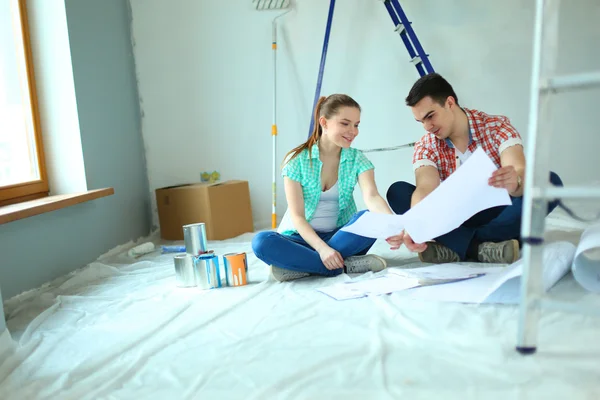 Junges Paar sitzt auf dem Boden und rechnet über seine Ersparnisse — Stockfoto