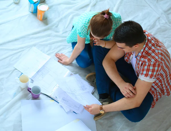 Jong koppel zittend op de vloer met appartement plan — Stockfoto