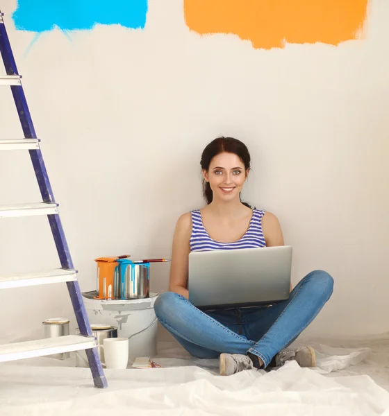Portrait de jeune femme tout en peignant un nouvel appartement, assis avec ordinateur portable — Photo