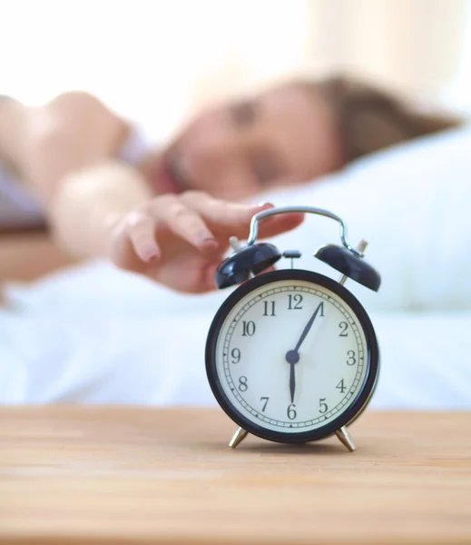 Young sleeping woman and alarm clock in bedroom at home Stock Picture