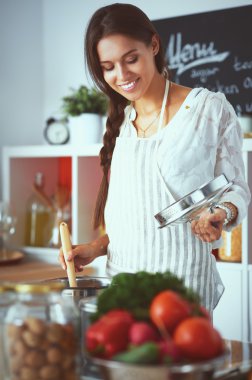 Mutfakta ahşap kaşıkla yemek pişiren kadın