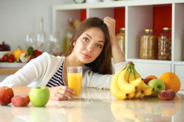 Genç bayan mutfakta masanın yanında oturuyor.