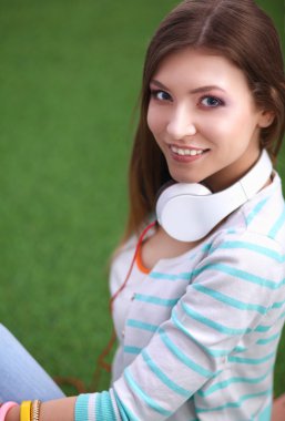 Yeşil çimenlerin üzerinde oturan güzel genç kadın