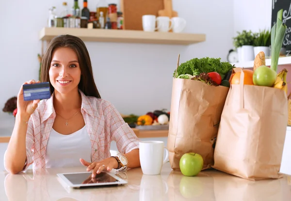 Smiling woman online shopping using tablet and credit card in kitchen — Stock Photo, Image