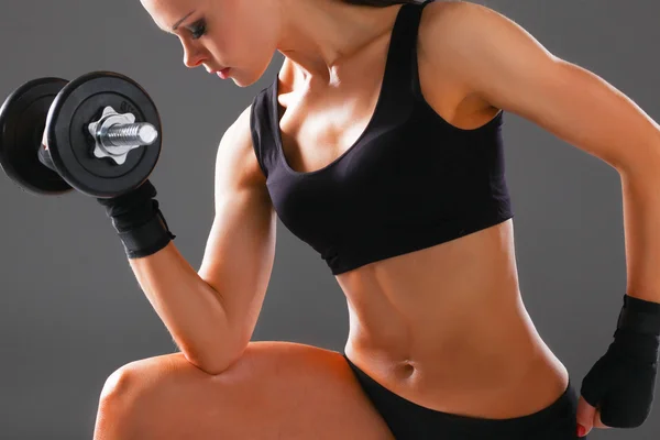 Атлетичная женщина накачивает мускулы гантелями — стоковое фото