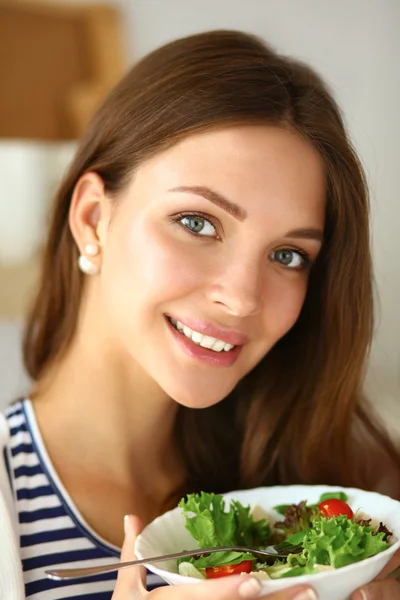 Giovane donna mangiare insalata e tenere un'insalata mista — Foto Stock