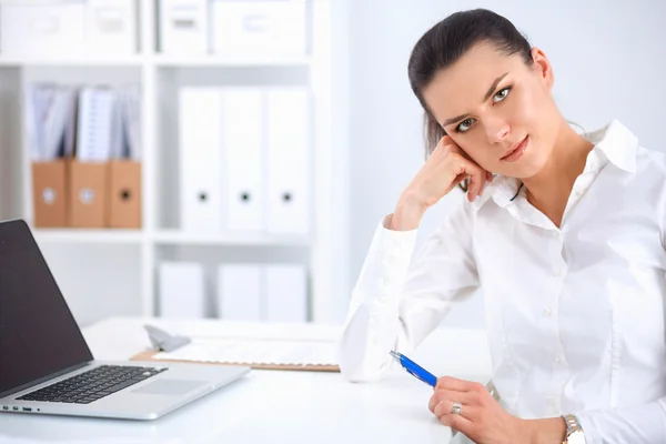 Attractive businesswoman sitting on a desk with laptop in the office — Stock Photo, Image