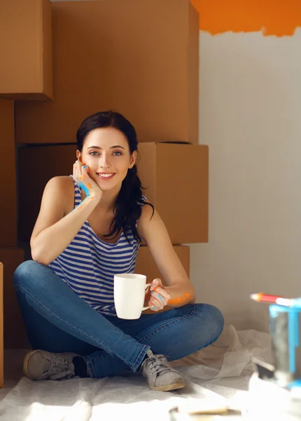 Женщина выбирает цвет краски из образцов для нового дома, сидя на деревянном полу — стоковое фото