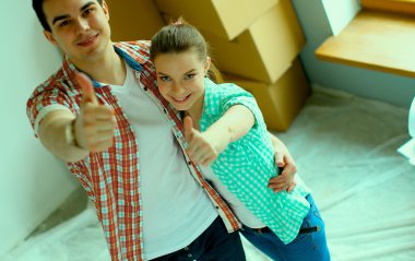 Genç Çift başparmak göstermek yukarıya onların yeni modern tasarım evinde mutlu