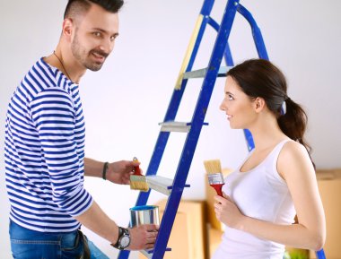 Mutlu gülümseyen genç çift boya iç cephe yeni evin portresi