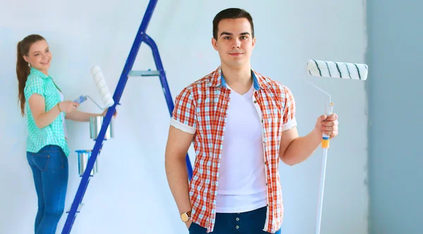 Retrato de feliz sorrindo jovem casal pintura parede interior da nova casa — Fotografia de Stock