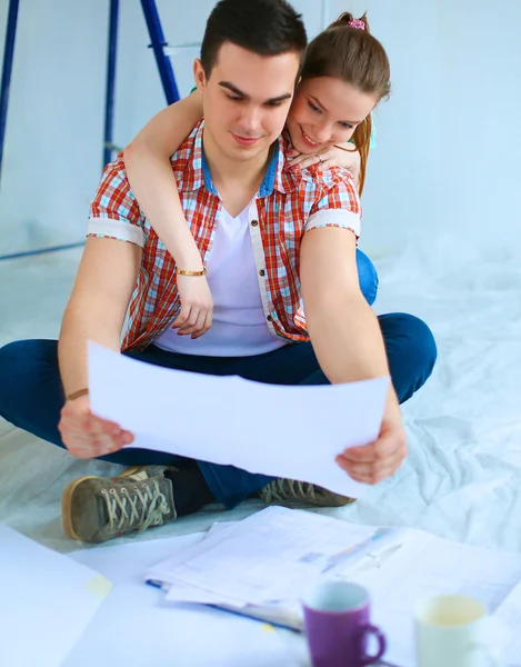 Junges Paar sitzt auf dem Boden mit Wohnungsgrundriss — Stockfoto