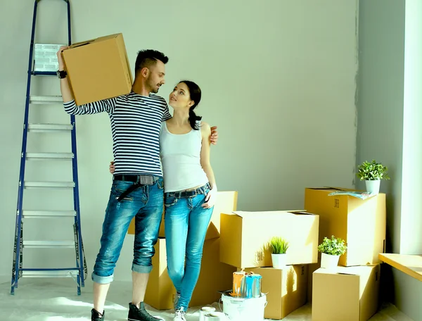 Felice giovane coppia disimballaggio o scatole di imballaggio e trasferirsi in una nuova casa — Foto Stock