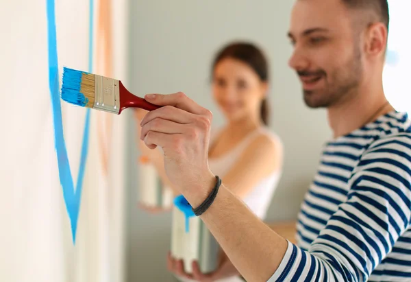 Ritratto di felice sorridente giovane coppia pittura parete interna della nuova casa — Foto Stock