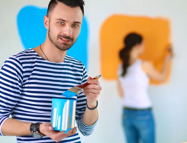 Portret van gelukkig interieur wand via lachende jong koppel-schilderij van nieuwe huis — Stockfoto