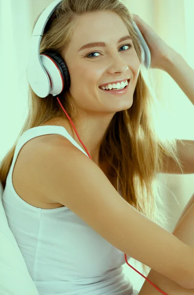 Retrato de mulher bonita de manhã ouvindo música sentada na cama em casa — Fotografia de Stock