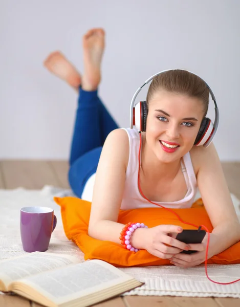 Ung kvinna liggande på golvet och lyssnar på musik — Stockfoto